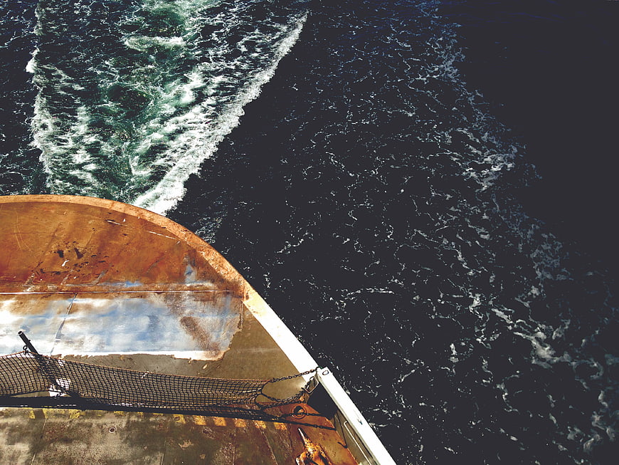 Aerial View of Rusty Boat Bow Cutting Through Dark Ocean Water