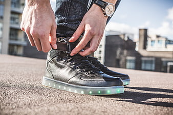 Man tying black LED sneakers on urban rooftop