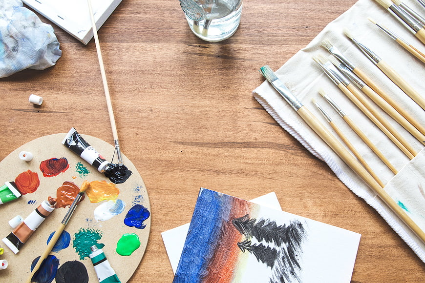 Flat lay of colorful painting supplies on wooden table