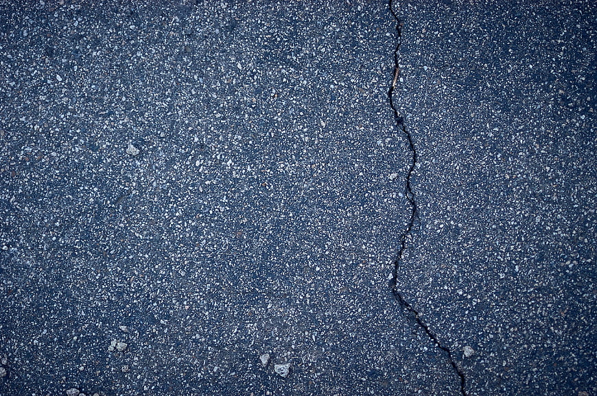 Close-up of cracked asphalt road surface texture