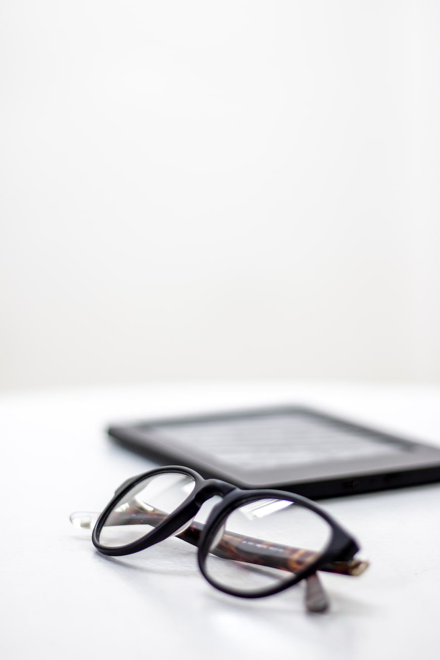 Reading Glasses and E-Reader on White Surface