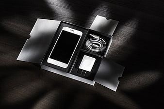 White Smartphone Unboxing with Charger and Cable on Dark Wood
