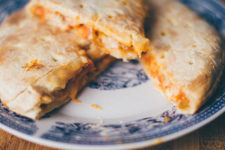 Close-up of cheesy calzone slices on a blue and white plate