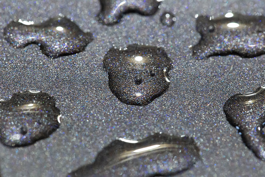 Macro shot of water droplets on dark glittery surface