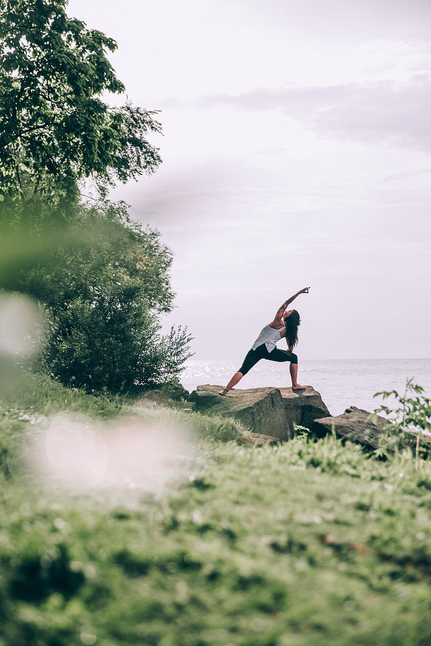 Woman doing yoga on rocks by the ocean