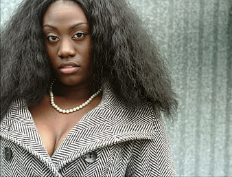 Portrait of stylish woman with afro hair and herringbone coat