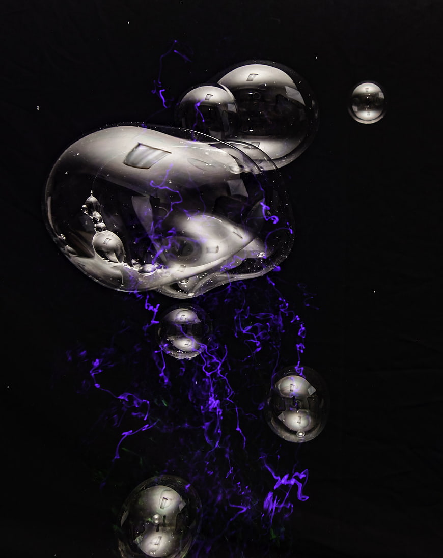 Abstract purple ink swirling in clear water bubbles on black background