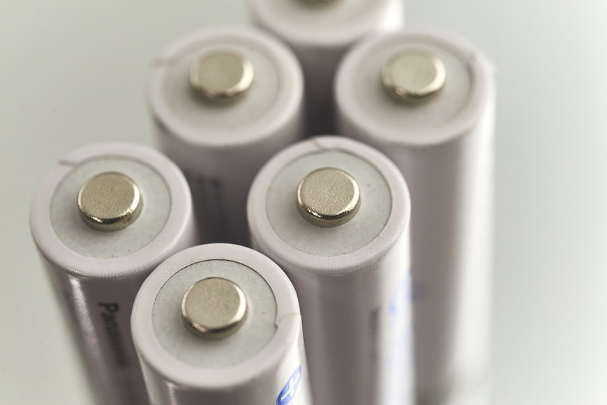 Close-up of white cylindrical batteries with positive terminals