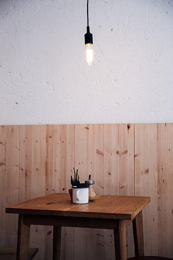 Minimalist wooden table with coffee cup and hanging light bulb