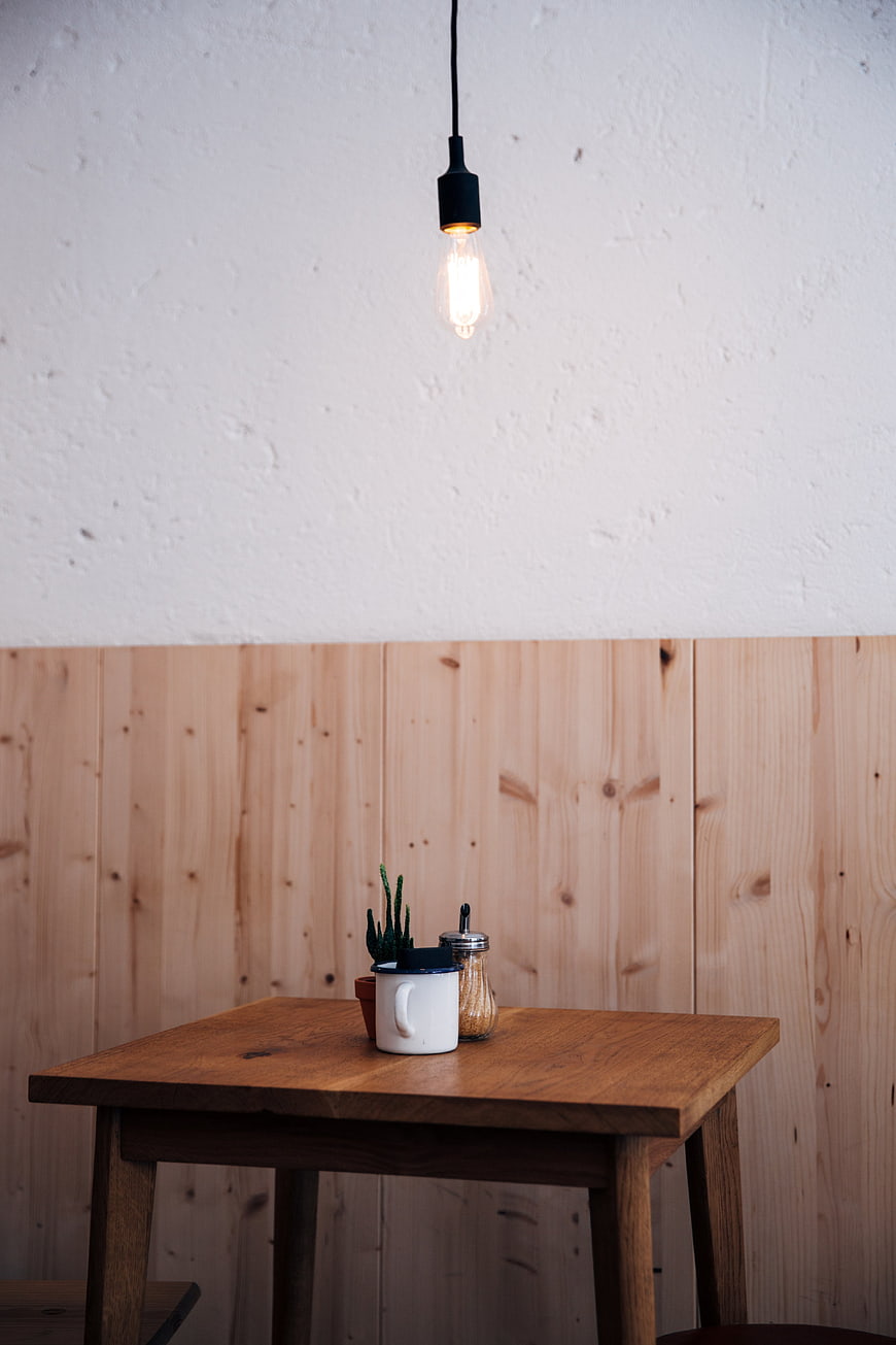 Minimalist wooden table with coffee cup and hanging light bulb