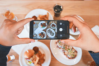 Hands taking photo of food on smartphone at restaurant