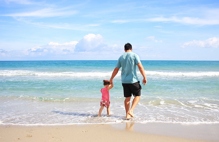 Father and Daughter Walking Hand in Hand on Beach