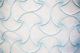 Close-up of white fabric with light blue scalloped embroidery pattern