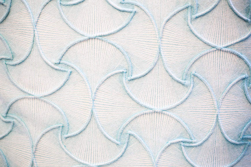 Close-up of white fabric with light blue scalloped embroidery pattern