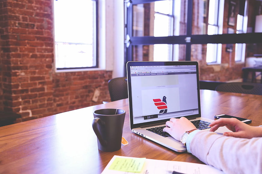 Person working on laptop in modern office with coffee