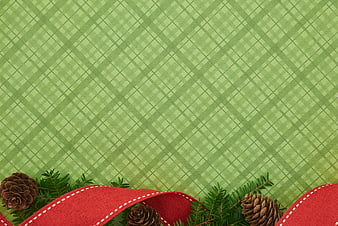 Green plaid background with red ribbon and pine cones