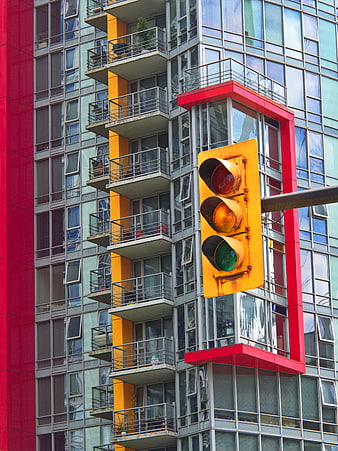 Yellow Traffic Light Against Colorful Modern Apartment Building