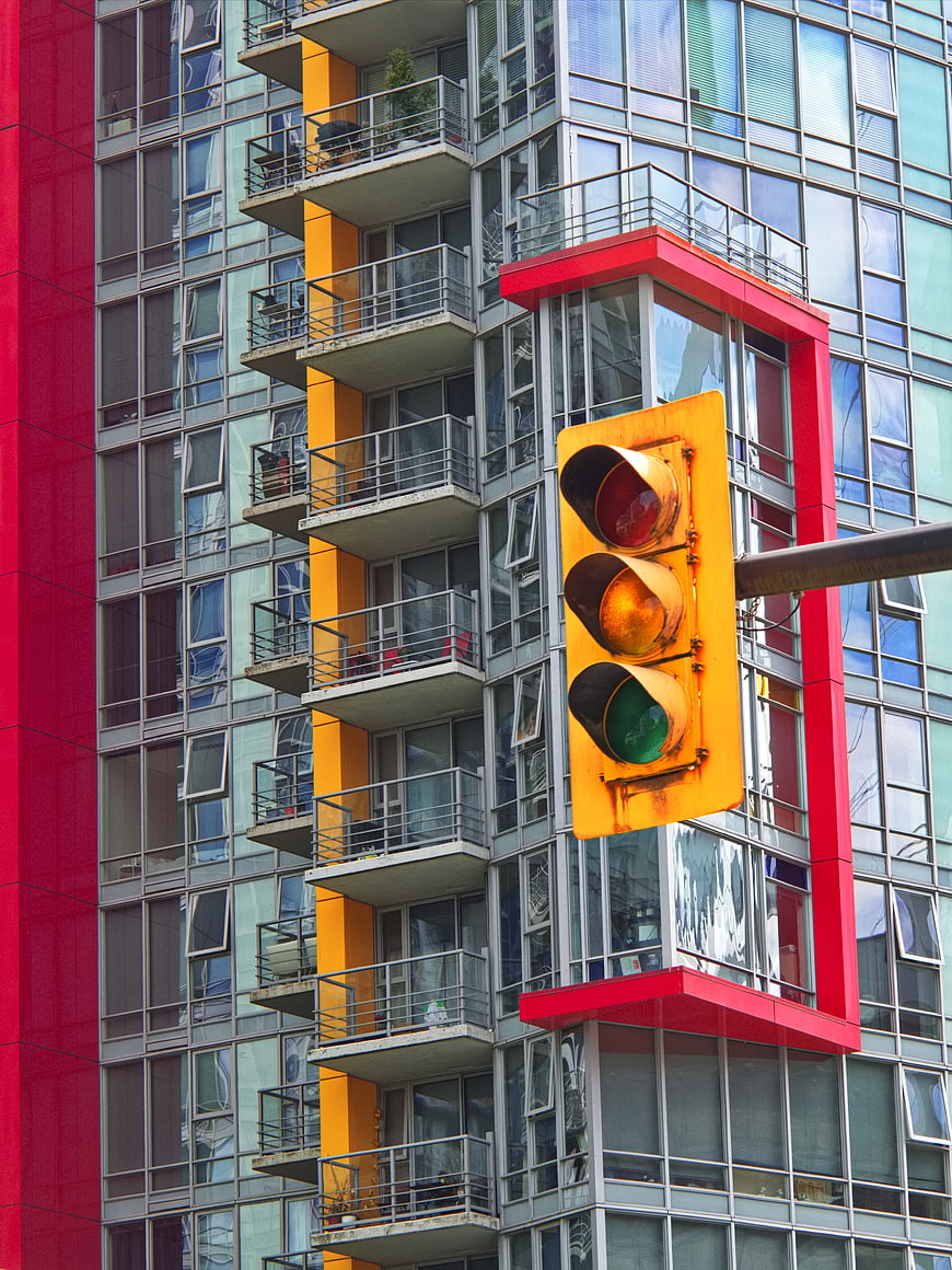 Yellow Traffic Light Against Colorful Modern Apartment Building