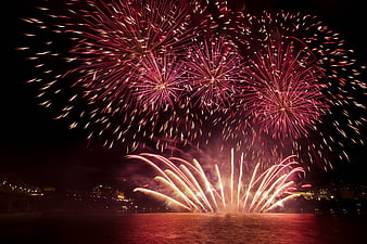 Vibrant red fireworks exploding over city skyline at night