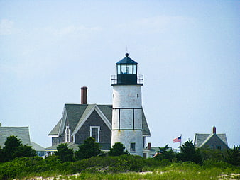 White Lighthouse with Coastal Houses and American Flag