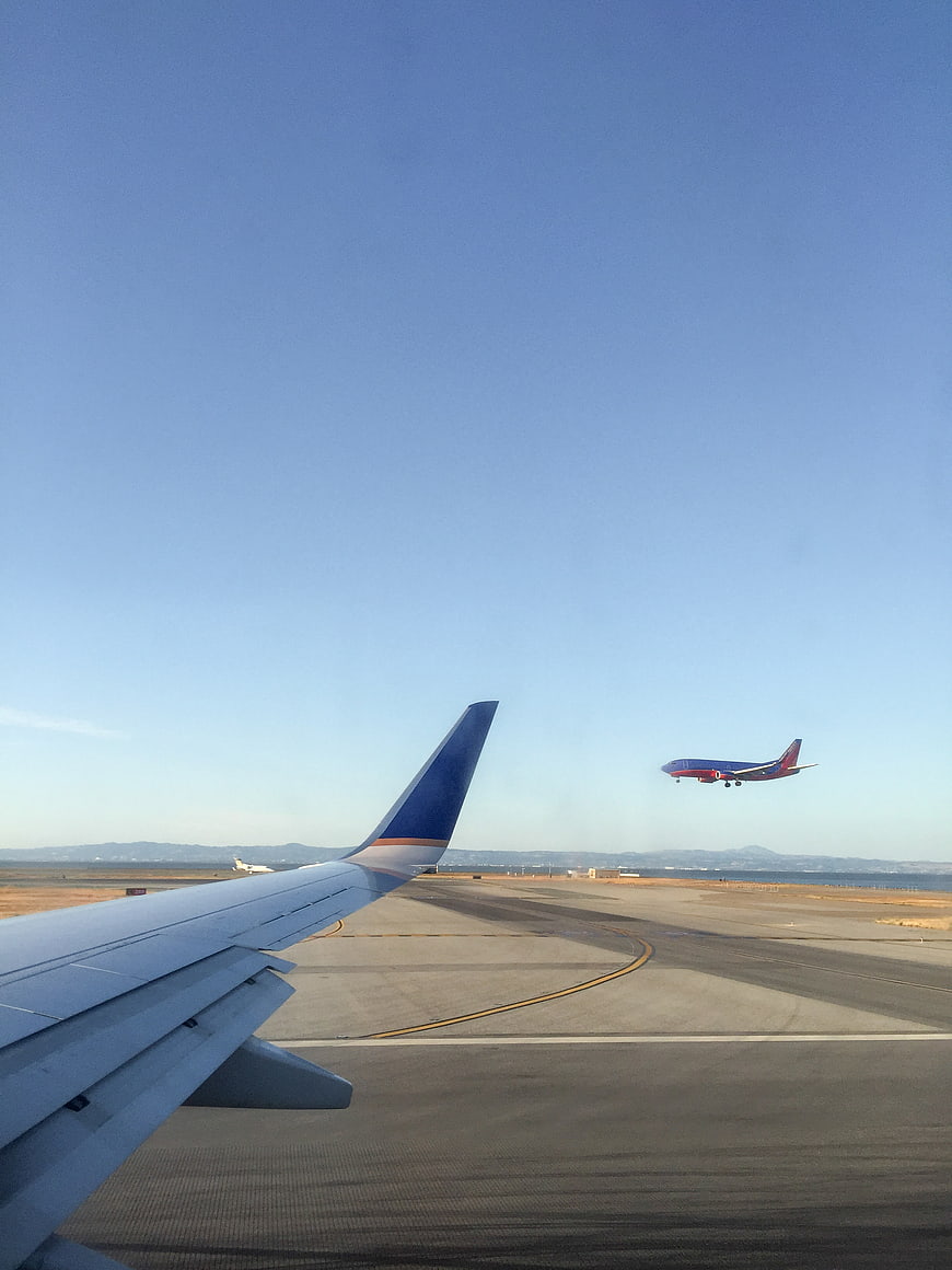 Airplane Wing View with Landing Jet on Runway