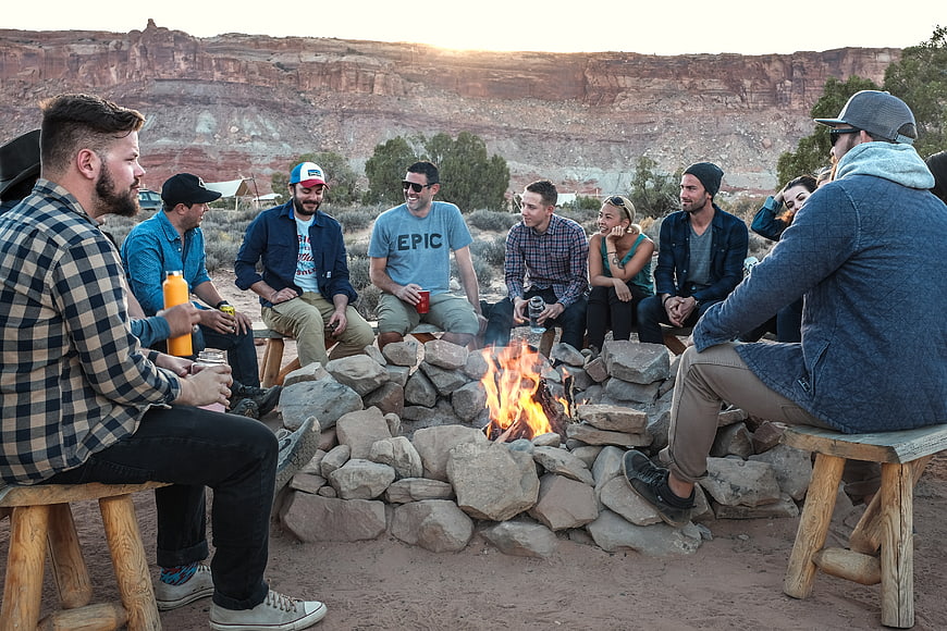 Group of friends sitting around campfire in desert canyon