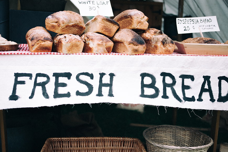 Fresh Bread Market Stall with Handwritten Sign and Wicker Baskets