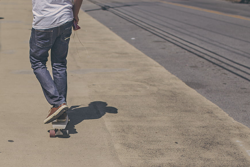 Skateboarder Riding Down Sidewalk on Sunny Day
