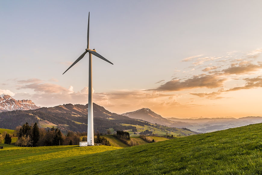 Wind Turbine on Green Hillside at Sunset
