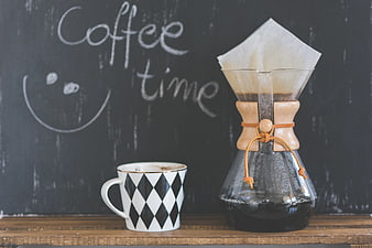 Chemex coffee maker and patterned cup on wooden shelf