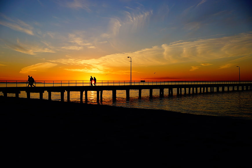 Silhouetted Couple Walking on Pier at Golden Sunset
