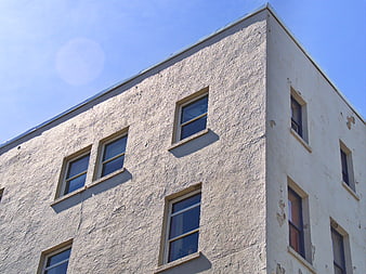 Low angle view of weathered white building facade with windows