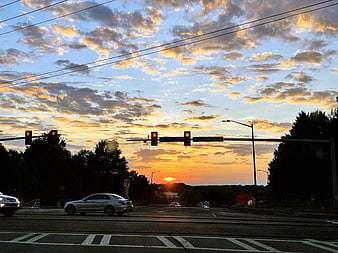 Sunset over suburban intersection with traffic lights and cars