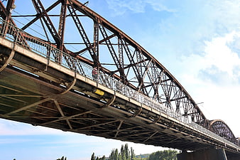 Low angle view of rusty steel truss bridge against blue sky