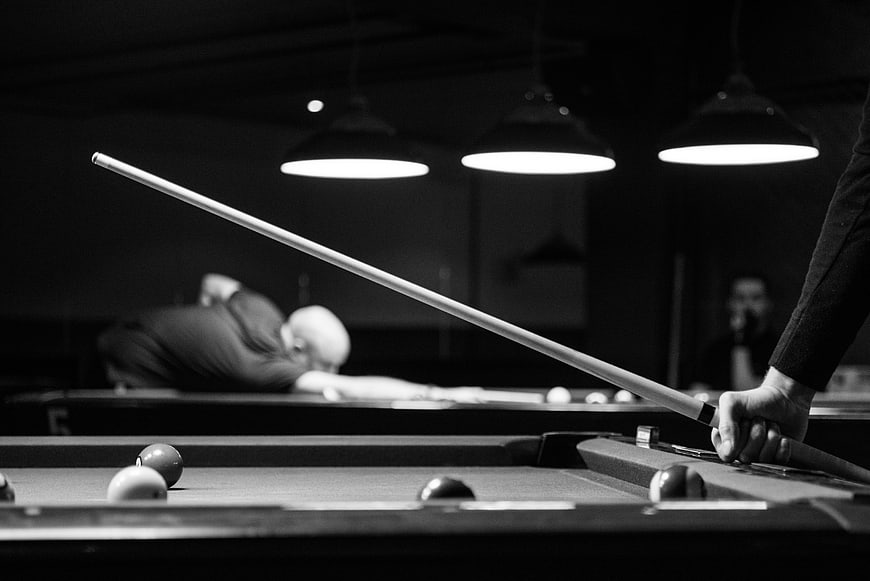 Black and white pool hall scene with cue stick and players