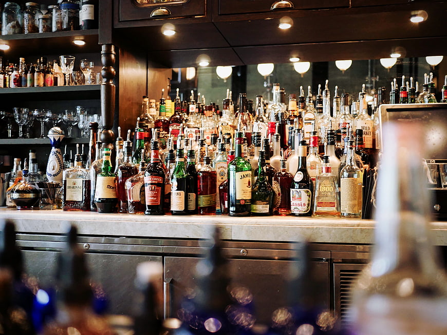Well-stocked bar counter with liquor bottles and bokeh lights