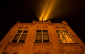 Low angle view of brick building with rooftop spotlights at night