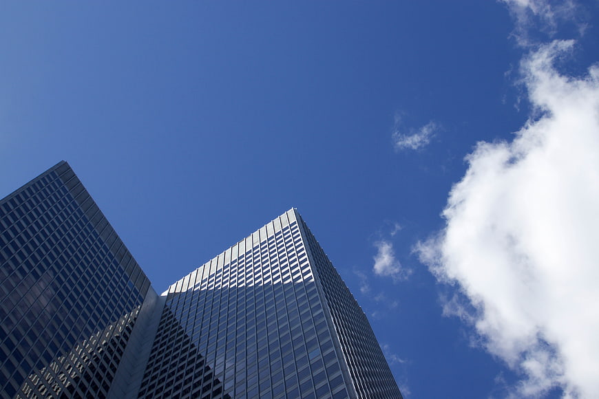 Low angle view of modern glass skyscrapers against blue sky