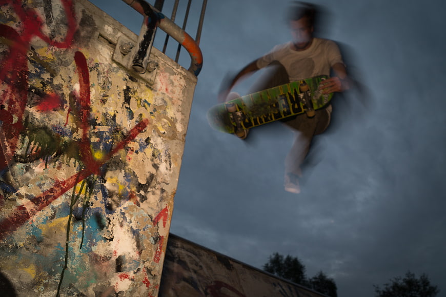 Skateboarder performing trick with motion blur against graffiti wall