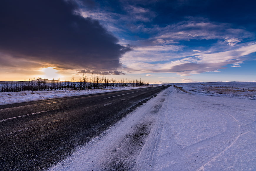 Snowy Winter Road at Sunset with Dramatic Clouds