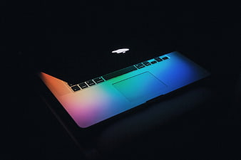 MacBook Pro with vibrant rainbow gradient lighting on dark background