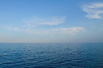 Calm Blue Ocean Horizon with Wispy Clouds and Moon