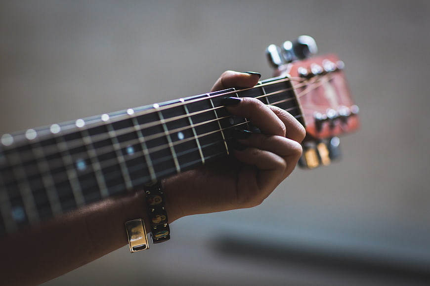 Close-up of woman playing ukulele with dark nail polish