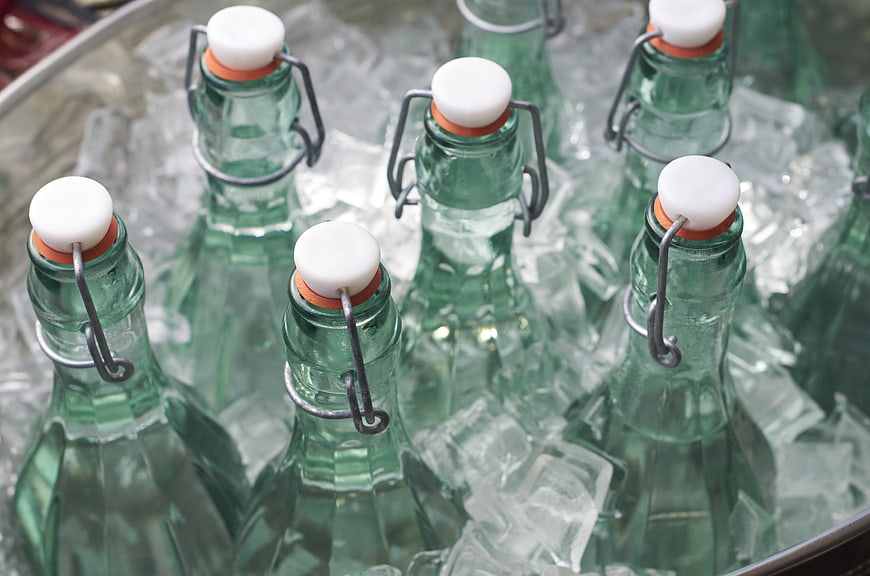 Green glass swing-top bottles chilling in ice bucket