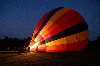 Colorful hot air balloon inflating at dusk with flame
