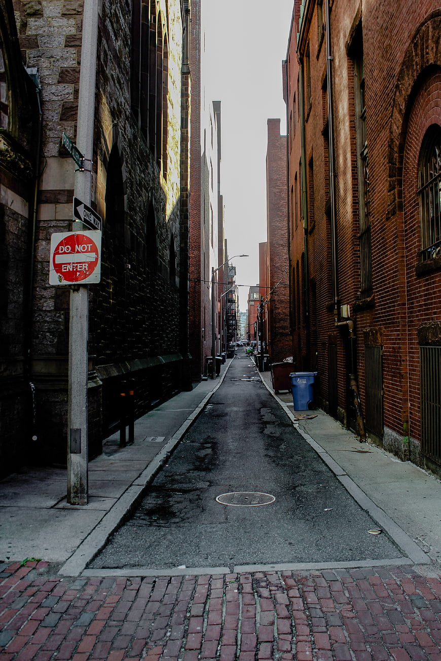 Narrow brick alleyway in urban city with do not enter sign