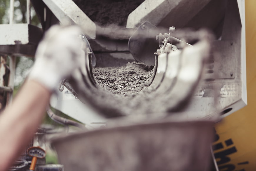 Worker operating concrete mixer machine on construction site