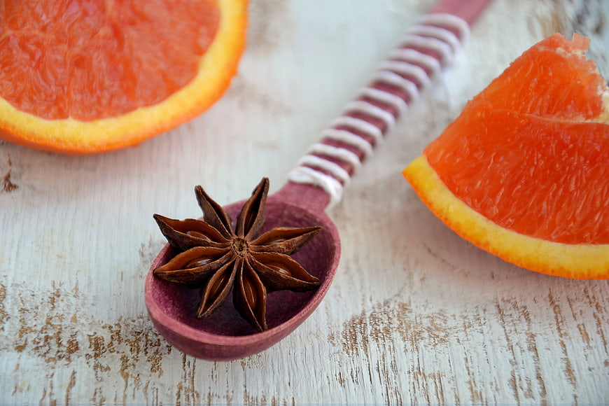 Star anise in wooden spoon with sliced blood orange