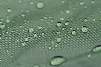 Macro shot of water droplets on green waterproof fabric