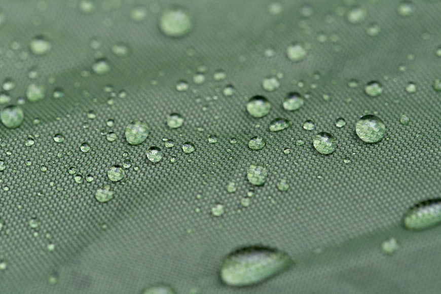 Macro shot of water droplets on green waterproof fabric